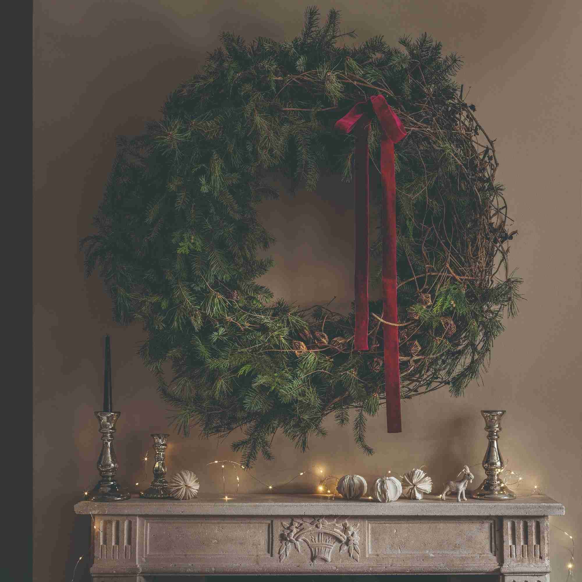 Fireplace decorated with a large wreath and restrained festive lighting.