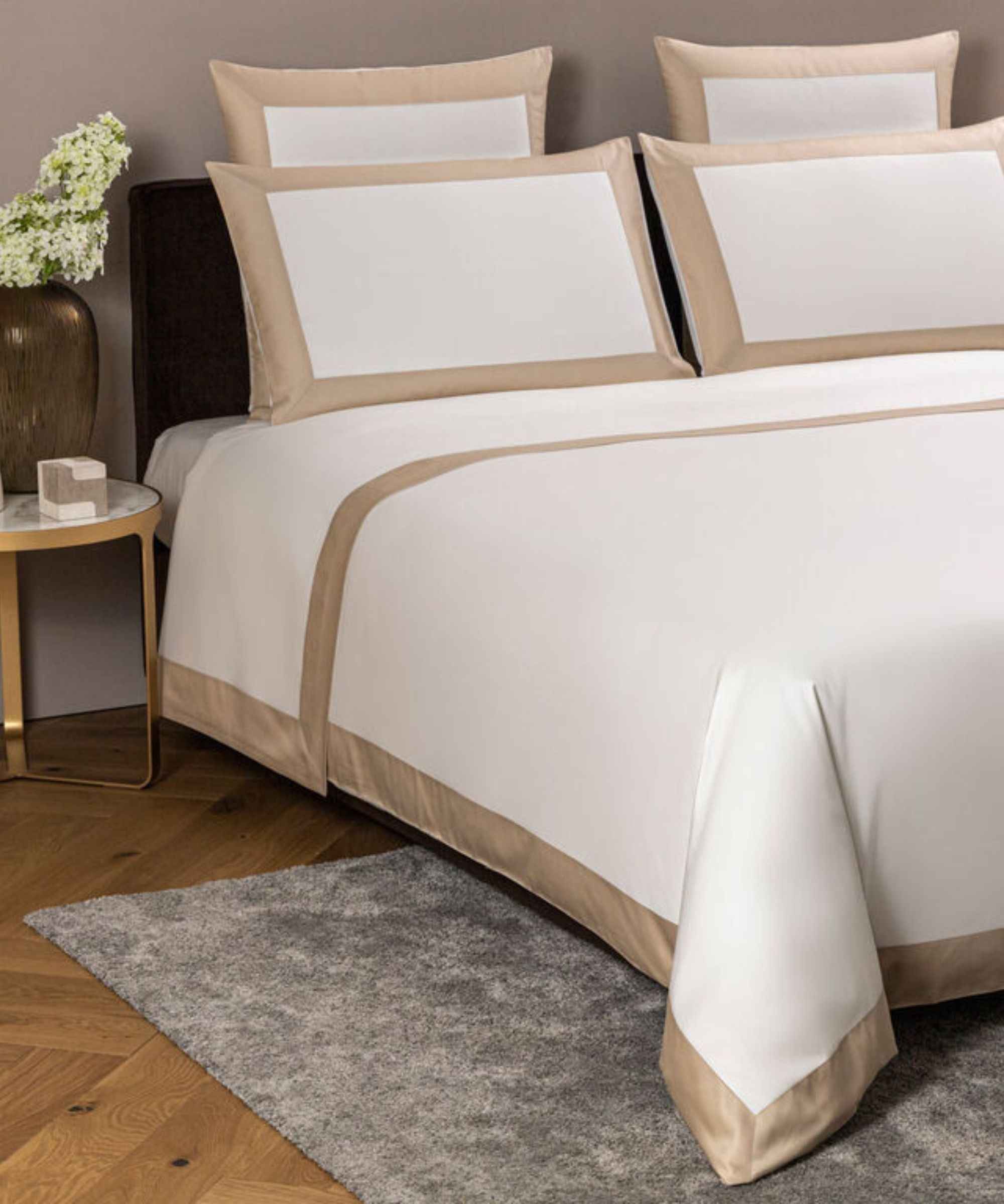 Frette Bold Bedding Collection on a bed against a gray wall.