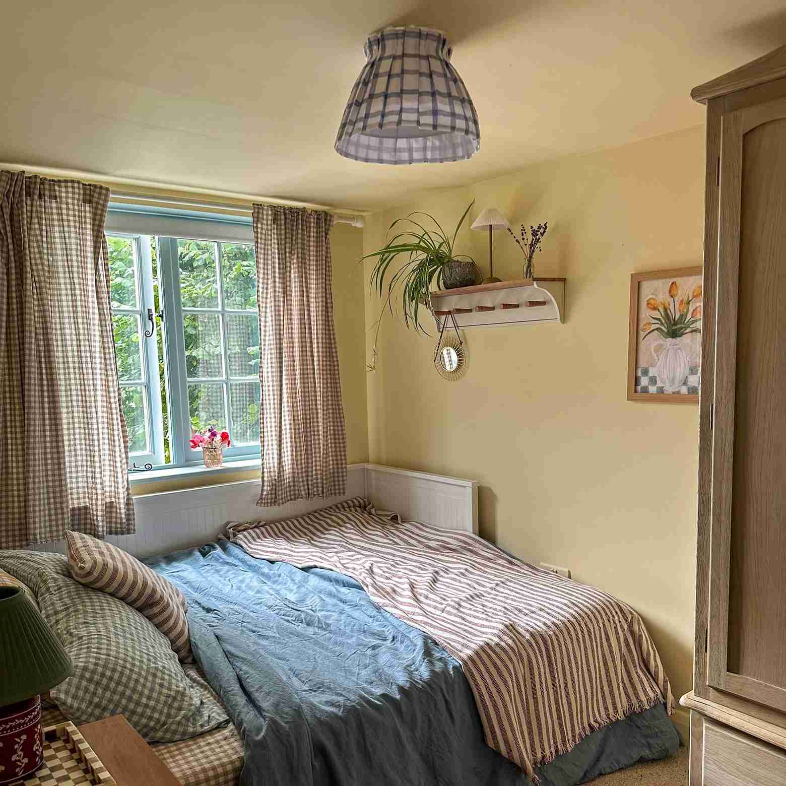 Yellow bedroom with striped and checked bedding in Lara Winter's cottage.