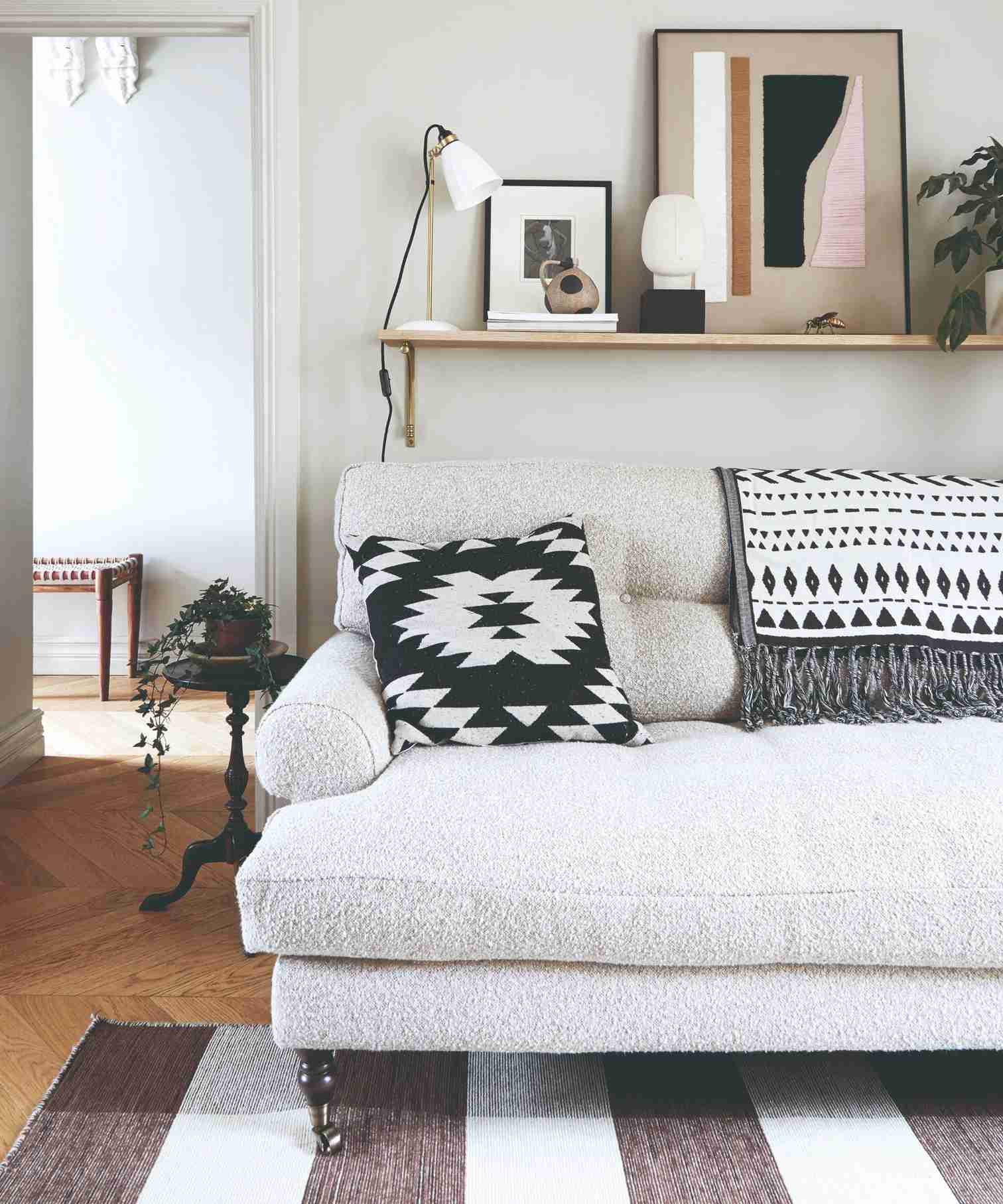 An off white-painted living room with a cream boucle sofa and a striped black and white rug