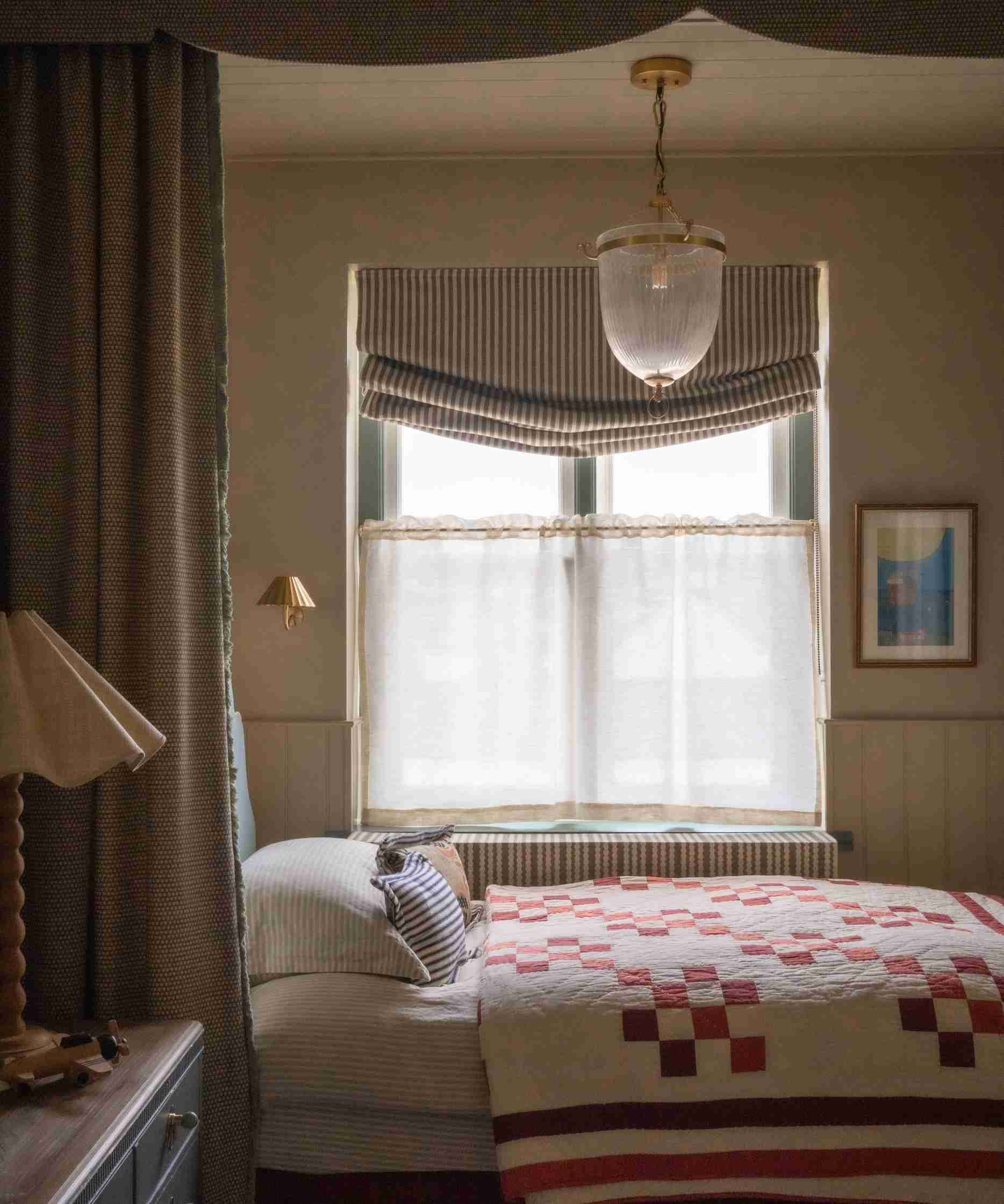 nook canopy bed by a window with a striped roman blind and a cafe curtain decorated with vintage decor