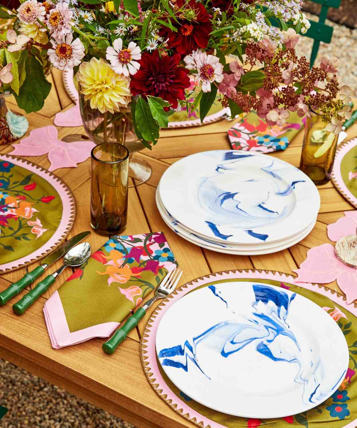 Wooden dining table with green bamboo-style flatware and colorful place settings.
